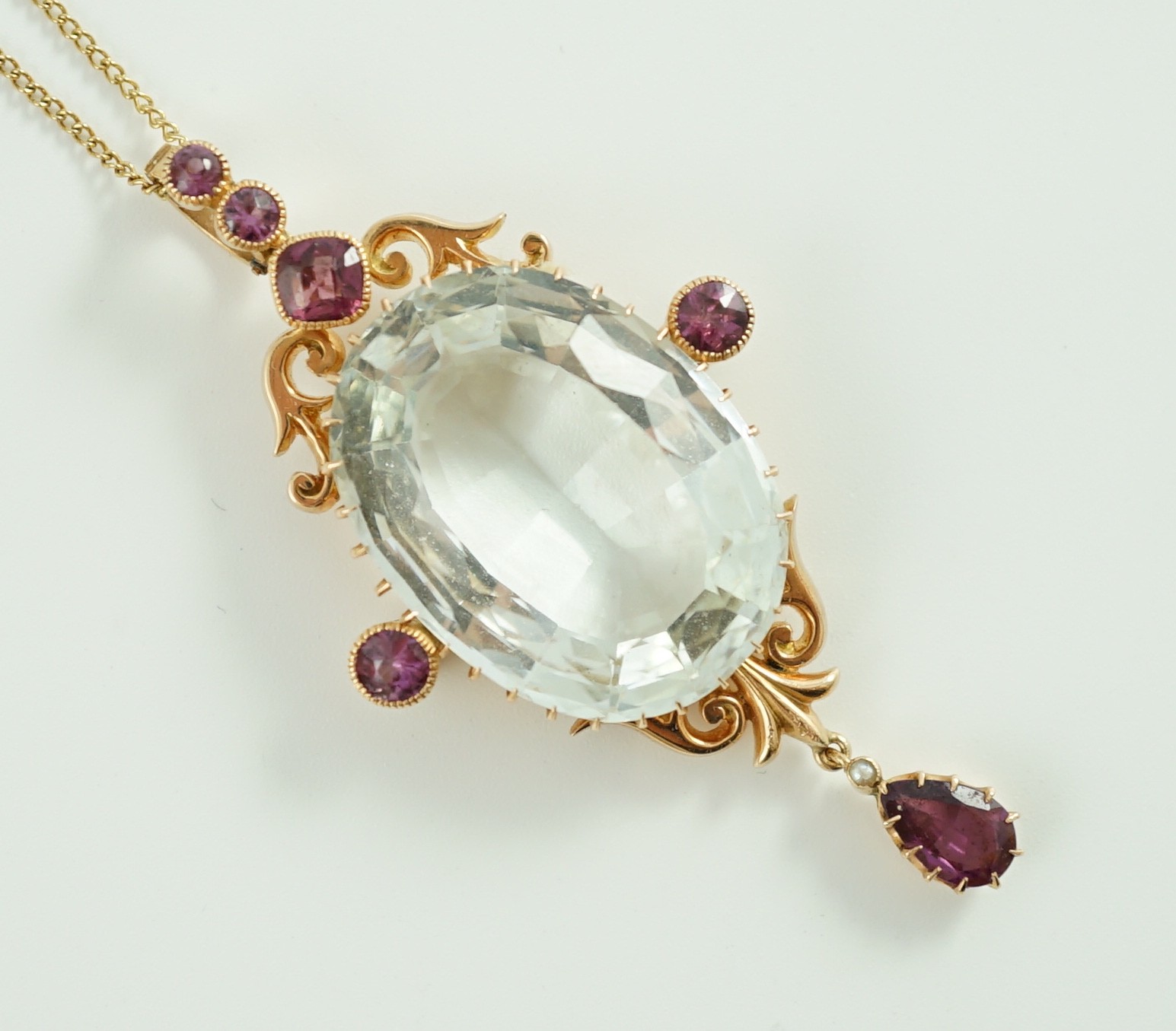 An early 20th century gold, aquamarine and garnet cluster set drop pendant, on a gold fine link chain